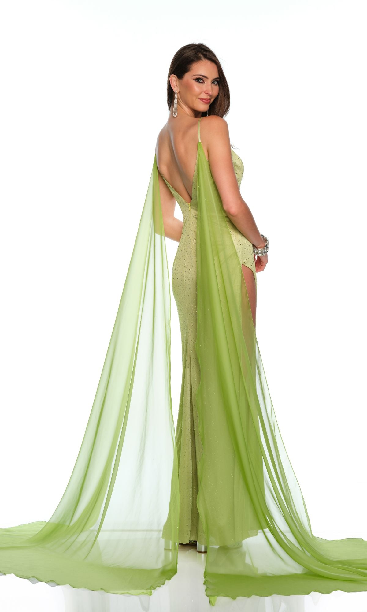 A woman poses elegantly against a white background wearing the Long Formal Dress 11597 by Dave and Johnny, featuring a green hue, v-neckline, open back, and long flowing chiffon panels.